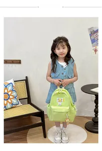 Close-up of a light green nylon kids backpack featuring a cute bear keychain detail
