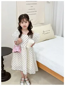 Détail d'une robe blanche à pois pour fille avec col carré et manches bouffantes