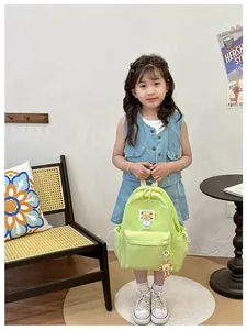 Detail of green nylon kids backpack with cute bear pendant and side drawstring pockets