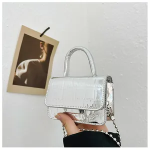 Macro detail of mini silver handbag featuring crocodile texture and metallic top handle