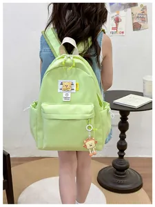 Rear view of girl wearing a lime green nylon backpack with cute bread-shaped charm