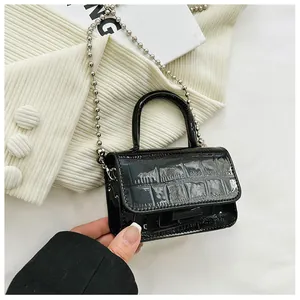 Close-up of black glossy crocodile pattern texture and silver bead chain on mini bag