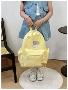 Close-up of yellow nylon kids backpack with stitching details and cute bear charm