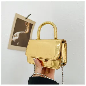 Detailed macro view of a metallic gold mini bag featuring embossed crocodile texture