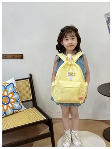 Detailed shot of yellow children's backpack with cartoon bear patch and lion pendant