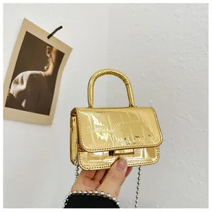 Detail of mini gold handbag with crocodile texture and metallic bead chain strap