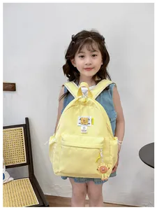 Detail of yellow nylon kids backpack with embroidered bear patch and fashion letter strap