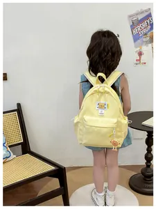 Rear view of a yellow cartoon bear backpack worn by a child in a cozy indoor setting