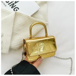 Detailed view of mini gold faux crocodile handbag with top handle and bead chain strap