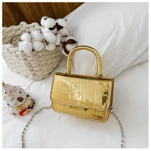 Detail of gold crocodile embossed mini handbag with silver bead chain strap and handle