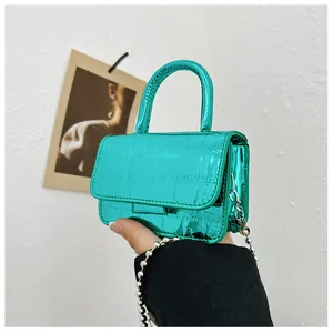 Macro view of metallic green mini bag with faux crocodile pattern and silver bead chain