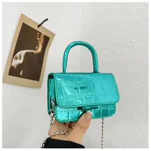 Macro view of metallic teal crocodile textured mini bag with silver ball chain strap