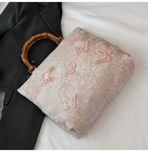 Detail der rosa Spitzentasche mit 3D-Schmetterlingen und Bambusgriff auf schwarzem Stoff