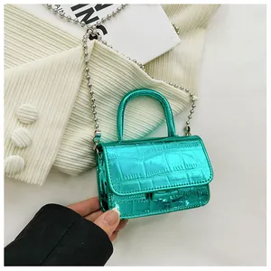 Close-up of mini crocodile pattern purse with metallic green finish and silver ball chain
