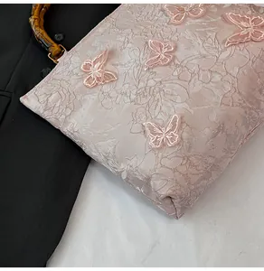 Detailansicht der rosa Jacquard-Tasche mit 3D-Spitzen-Schmetterlingen und Bambusgriff