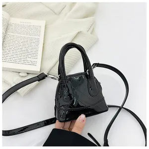 Détail d'un sac à main noir en cuir verni matelassé avec garnitures argentées et deux poignées