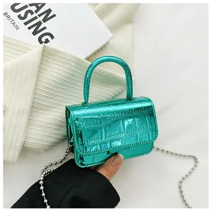 Detail of metallic green mini bag with crocodile texture and silver ball chain