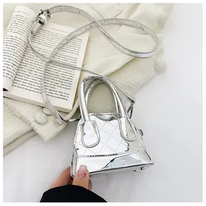 Gros plan d'un mini sac argenté matelassé avec finition métallisée sur tricot et livre