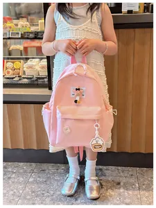 Close-up of pink nylon kids backpack with star charm and teddy bear pendant in bakery setting