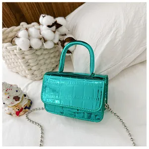 Detail of glossy metallic green crocodile pattern mini bag with silver chain strap