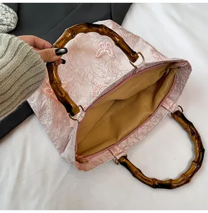 Makro-Detail der rosa Tasche mit Schmetterlings-Stickerei und Bambusgriff-Design