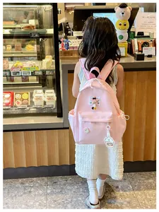 Pink kids backpack with star patch and cupcake pendant shown from the back view