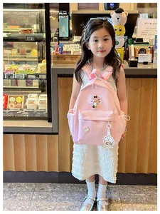 Close-up of pink children's school bag featuring star charms and cute cake pendant detail