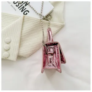 Close-up of metallic pink mini bag with glossy finish and silver bead chain strap