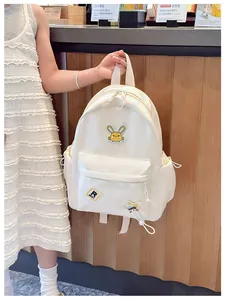 Detail view of cream nylon children backpack featuring cute rabbit and star badges on side