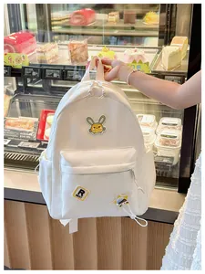 Detail of white nylon kids backpack with yellow rabbit embroidery and star pendant