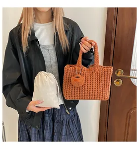 Close-up of orange-brown waffle knit tote bag with handmade tag and drawstring pouch