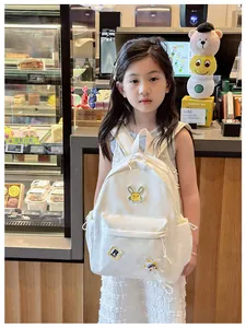 Kid back view of a white nylon school backpack with rabbit patch in a cafe setting