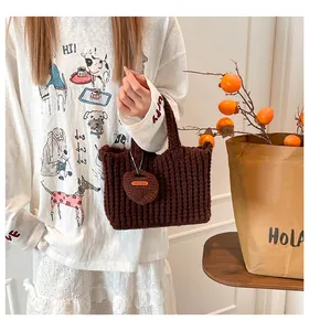 Close-up of brown knit tote bag featuring vertical textures and a heart-shaped handmade charm