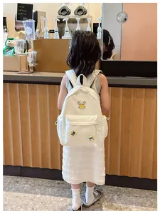 Detail of white nylon kids backpack with cartoon rabbit patch and star charm accessory