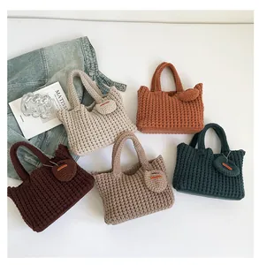 Flat lay of knit tote bags in five colors with matching heart charms and waffle texture