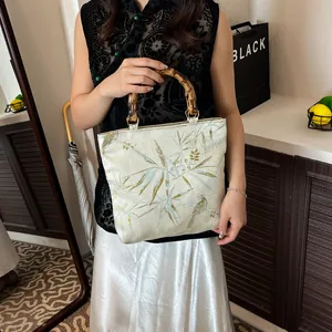 Elegante Tasche im China-Stil mit Bambusgriffen und Vogelstickerei auf cremeweißem Stoff