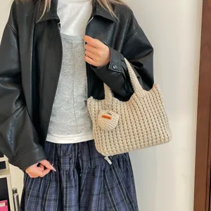 Chic beige honeycomb knit tote bag with heart charm shown on model in a casual outfit
