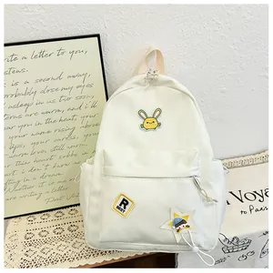 Close-up of beige nylon kids backpack with rabbit embroidery and cute star doll pendant