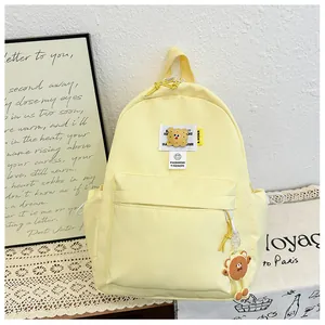 Detail of light yellow canvas backpack featuring cute cookie patch and bear keychain