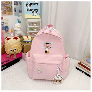 Detail of pink nylon school bag with star embroidery and cute cake-shaped pendant