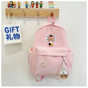 Detailed view of pink school backpack with star patch and cute cupcake charm accessory