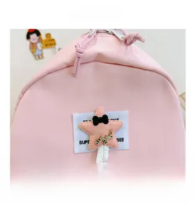 Detailed macro view of the pink nylon backpack featuring a star patch and Angel text detail