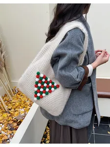 Detailed knit texture of white winter tote bag featuring festive pom-pom tree pattern