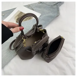 Détail du sac seau marron foncé avec cordon de serrage et coutures blanches contrastées