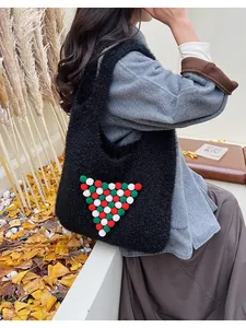 Close-up of black fuzzy tote bag with festive color pom-poms on soft knit texture