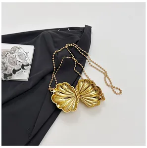 Detail of a golden shell evening clutch bag with glossy finish and beaded chain strap