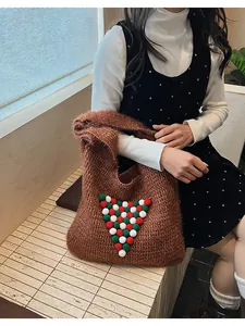 Detail of a brown knit tote bag featuring festive red and green decorative pompoms