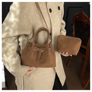 Sac seau rétro en daim marron avec pochette assortie porté par un mannequin en intérieur
