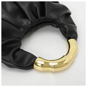 Detail of black pleated dumpling bag with golden semicircular metal handle