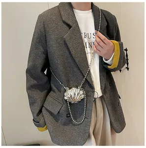 Silver shell-shaped mini bag with bead chain strap worn with a tailored grey blazer